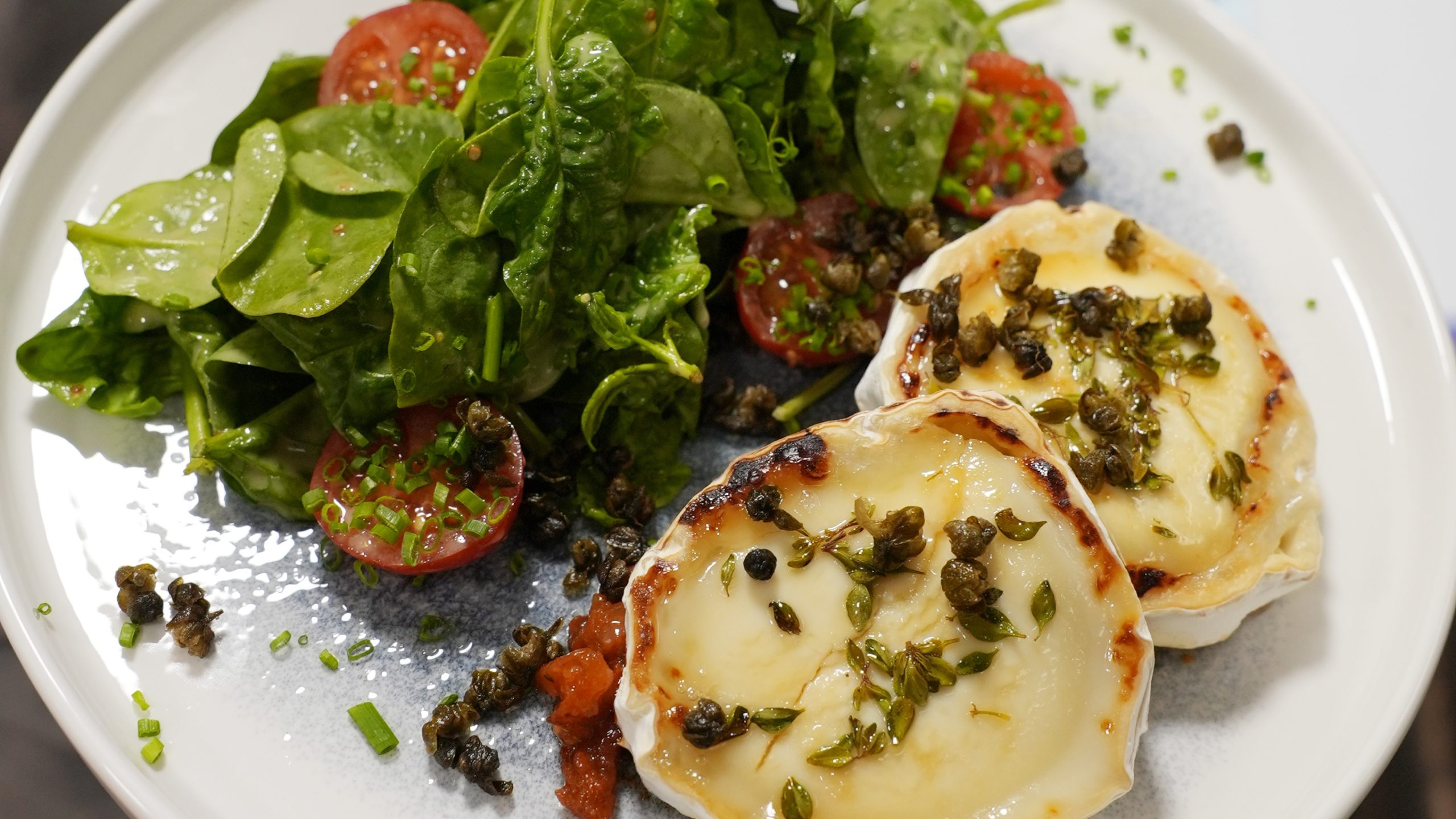 Ein Teller mit Gratiniertem Ziegenkäse, Cassissenf, Birnenchutney und Spinat-Salat